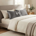 Dark grey satin pillowcases on a made bed